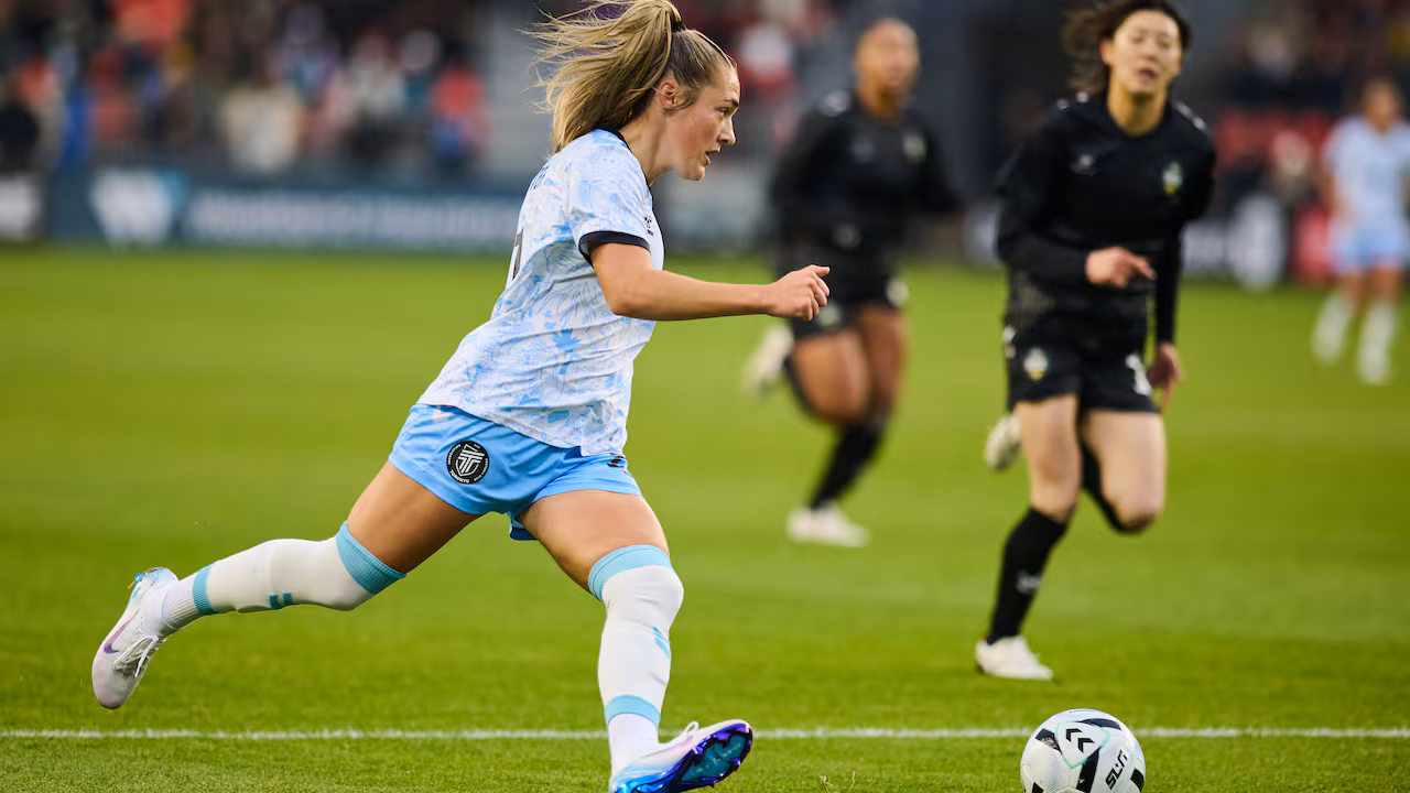 A female soccer player runs with the ball during a match.