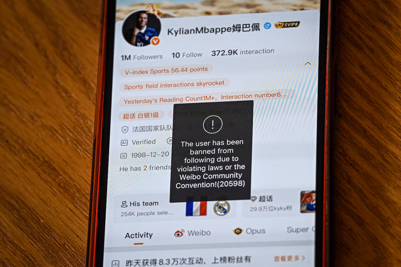 A smartphone is displayed on a table with a social media app on the screen.